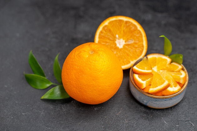 柑橘在黑暗的桌子上 整个柠檬上鲜切的橙子一半的特写镜头深色封闭素食