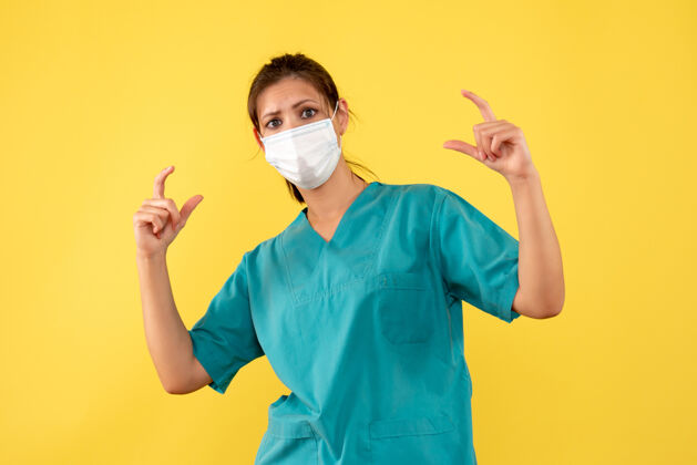 黄色前视图黄色背景上穿着医用衬衫和面罩的女医生人脸外套