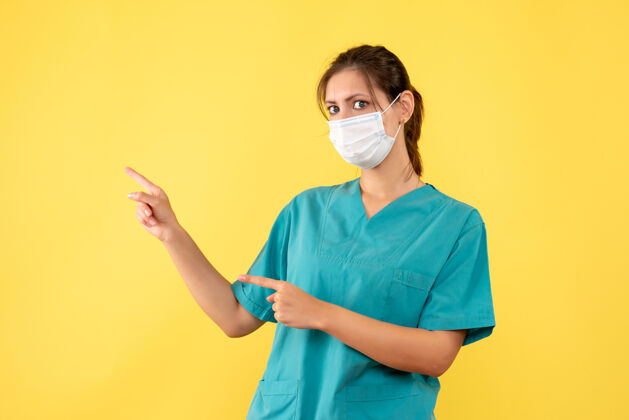 病毒前视图黄色背景上穿着医用衬衫和面罩的女医生人肖像专业