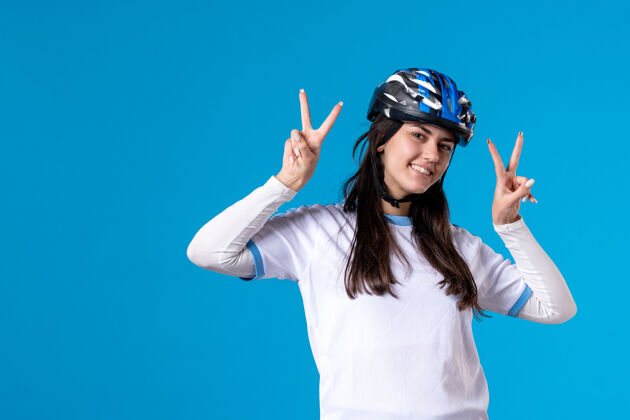 正面前视图穿着运动服的年轻女性 蓝色墙上戴着头盔年轻女性人物自行车