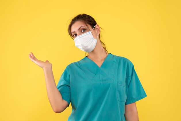 黄色前视图黄色背景上穿着医用衬衫和面罩的女医生正面专业脸
