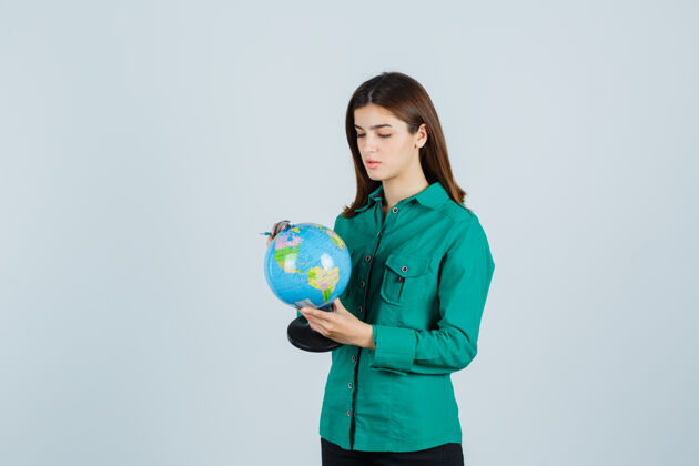水疗穿着衬衫的年轻女士手里拿着地球仪 仔细地看着 正前方肖像地球黑发