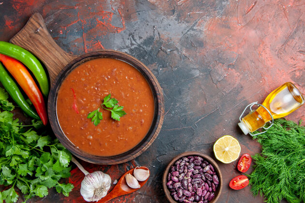 混合物番茄汤俯视图在一张五颜六色的桌子上的砧板上掉落的油瓶豆汤容器豆子