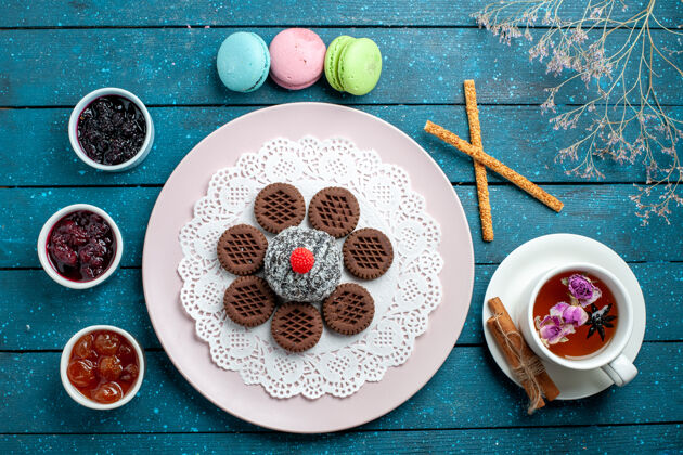 托盘俯瞰美味的巧克力饼干与果酱和茶杯上的蓝色乡村办公桌饼干茶饼干甜蛋糕糖餐点容器茶