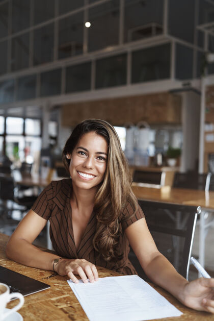 在线成功的西班牙裔女性微笑着在咖啡馆工作商业女性无线桌子