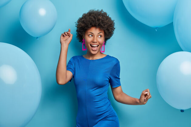 欢呼快乐无忧无虑的女人 穿着时髦的衣服 对着蓝色的气球摆出喜庆的姿势快乐风格节日