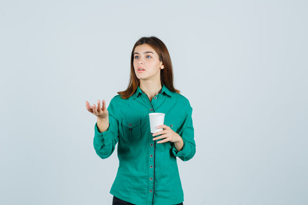 模特年轻的女士拿着一杯塑料咖啡 穿着衬衫 以质疑的态度伸出手 目光集中正视图魅力人咖啡