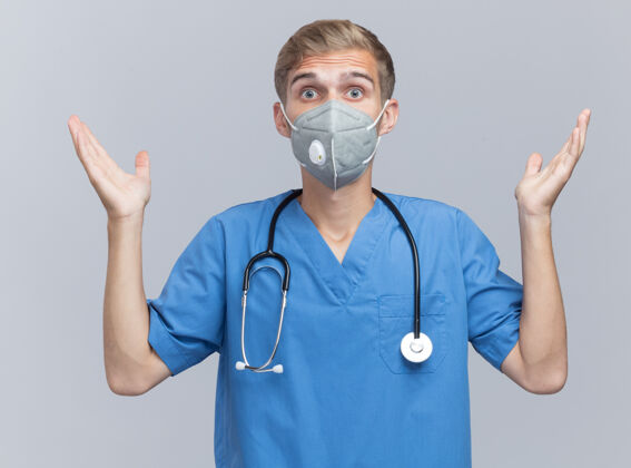 男性年轻的男医生穿着医生制服 戴着听诊器和医用口罩 双手被隔离在白墙上惊喜手制服
