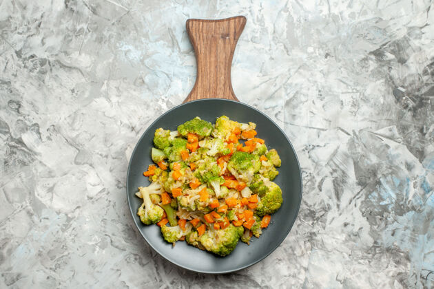 新鲜上图：白色桌子上的木质砧板上新鲜健康的蔬菜沙拉晚餐午餐胡椒