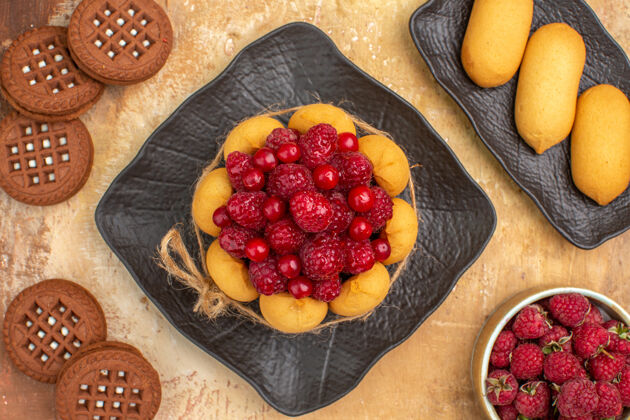 农产品一个礼物蛋糕和饼干在棕色盘子上水果在混合颜色的桌子上水果甜点覆盆子