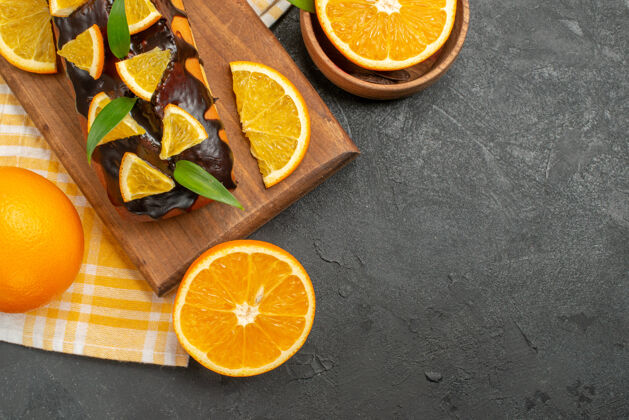 切块把整个软蛋糕和切好的带叶子的橙子放在深色的桌子上深色新鲜健康