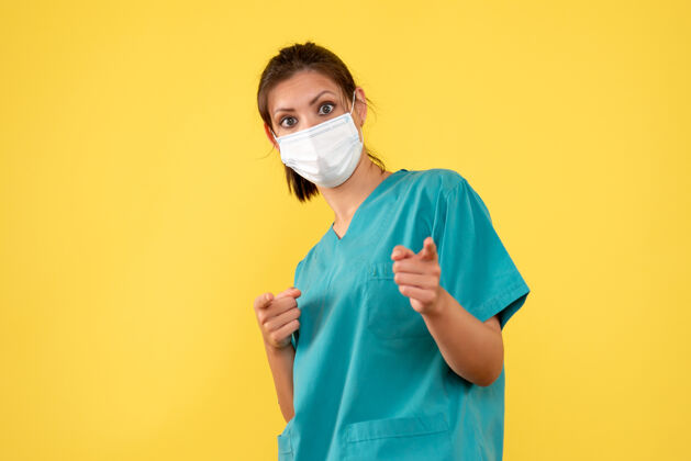 成人前视图黄色背景上穿着医用衬衫和面罩的女医生健康视图脸