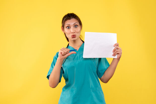 黄色正面图黄色背景下穿着医疗衫的女医生拿着纸分析微笑纸视图