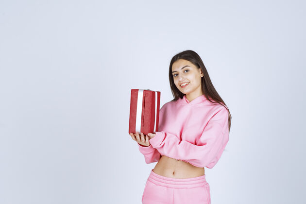 聪明穿着粉色睡衣的女孩手里拿着一个红色长方形礼盒 看上去很满意庆祝服装年轻人