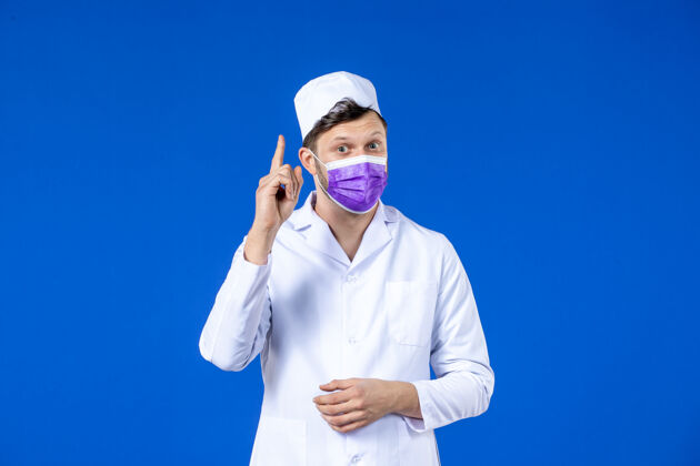 世卫组织穿着医疗服 戴着紫色面罩 对蓝色有想法的男医生的正视图大流行病毒诉讼