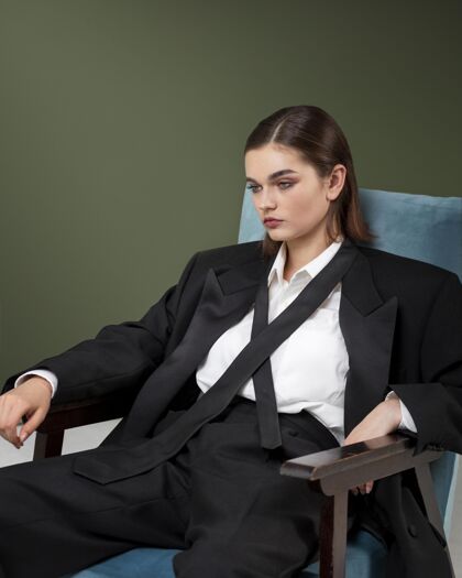 美丽优雅的女模特穿着夹克套装坐在扶手椅上全新的女性概念时尚魅力新女性