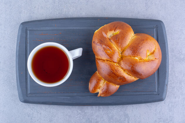 板早餐供应茶和甜面包在大理石表面的木板上小吃馒头茶