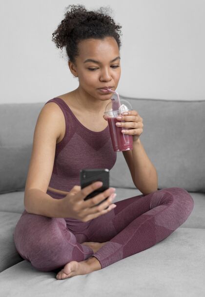 果汁健身女士一边用智能手机一边喝排毒果汁可口企业生活方式