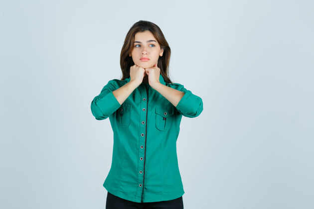 悲伤漂亮的年轻女士 穿着绿色衬衫 把拳头放在下巴下面 看起来很沮丧 正前方的景色成人孤独衬衫