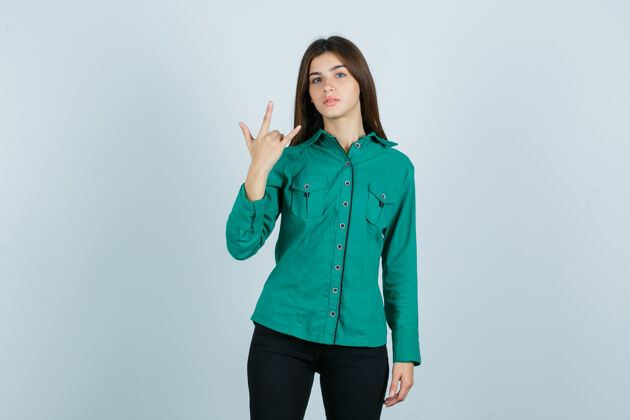 裤子身着绿色衬衫 长裤的年轻女性 展现出摇滚般的姿态和自豪的神情 俯瞰前方手势成人商业