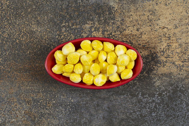 松脆的红碗里有美味的黄色糖果明亮的糖果小的