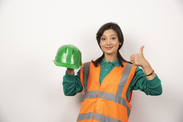 女士女工程师竖起大拇指 手持白色背景的头盔女性工人工作