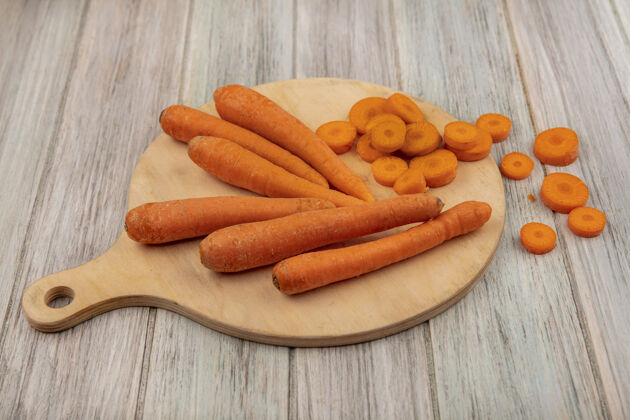饮食顶视图橙色根蔬菜胡萝卜与切碎的胡萝卜在一个灰色的木制厨房板表面人美味一餐