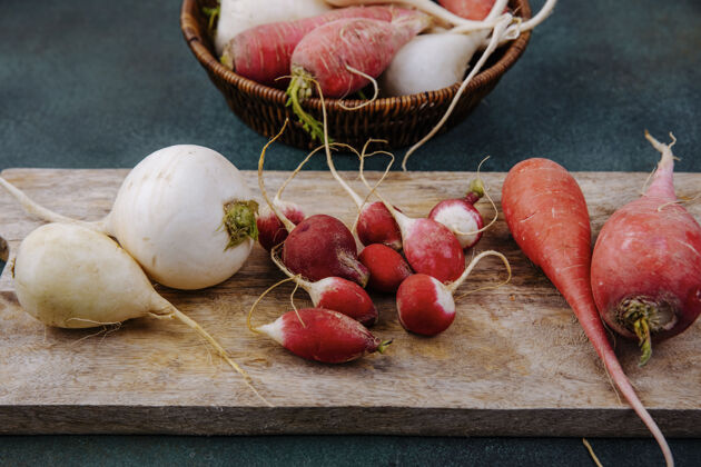 蔬菜顶视图新鲜的白色和粉红色的红色根蔬菜甜菜根在一个木制的厨房板上与萝卜在一个绿色的表面甜菜萝卜粉红