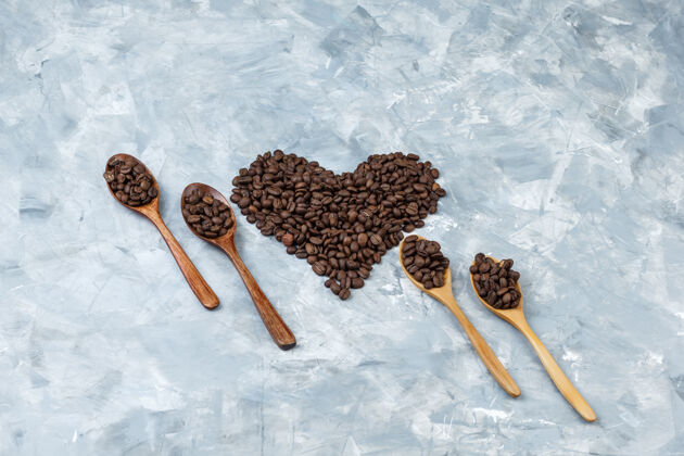 早餐把咖啡豆平铺在灰色灰泥背景上的木勺里水平谷物咖啡馆堆
