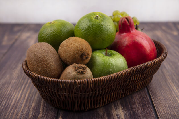 石榴在木墙上的篮子里放着桔子 猕猴桃 苹果和石榴景观猕猴桃食品