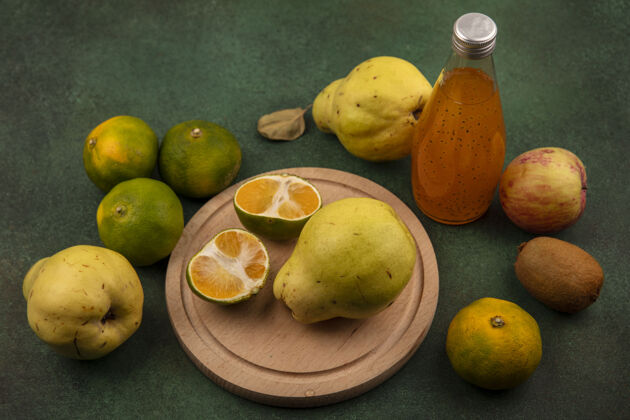 橘子侧视图橘子片与梨苹果猕猴桃和一瓶果汁的立场上的绿色墙壁瓶子橙子梨