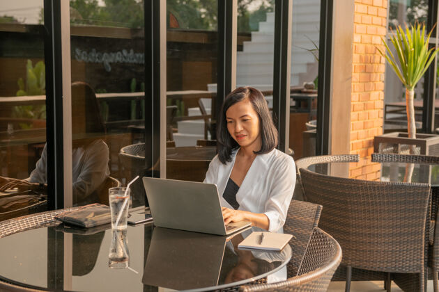 工作女商人在咖啡馆用笔记本电脑的画像人年轻人坐着
