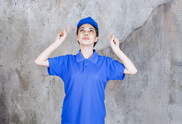 年轻人身着蓝色制服的女服务人员指着上方帽子上装快递员