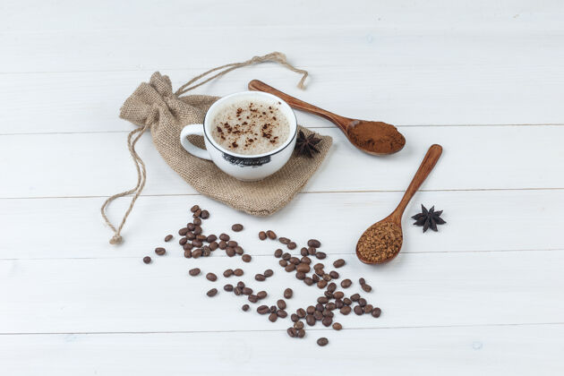卡布奇诺一些咖啡与磨碎的咖啡 香料 咖啡豆在一个木杯和麻袋背景 高角度的看法新鲜桌子
