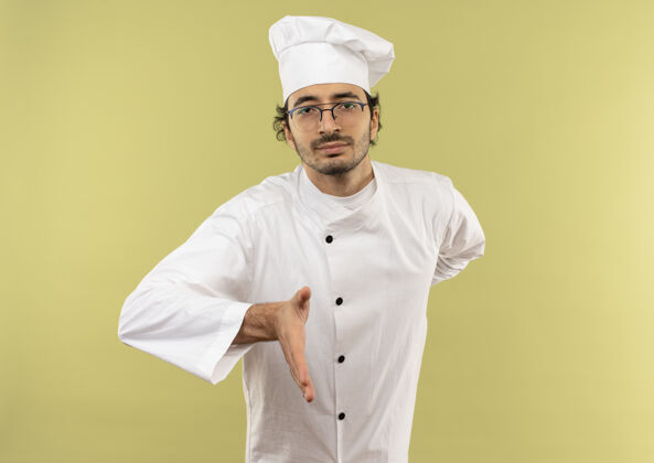绿自信的年轻男厨师穿着厨师制服 戴着眼镜伸出手来信心厨师男