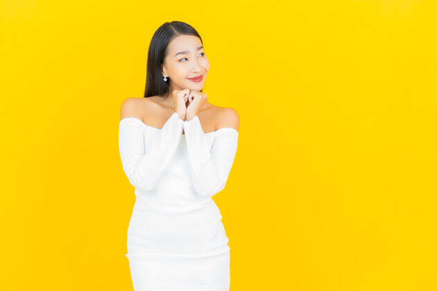 西装美丽的亚洲年轻商业女性在黄色墙壁上穿着白色裙子微笑的画像事业商业人士行政