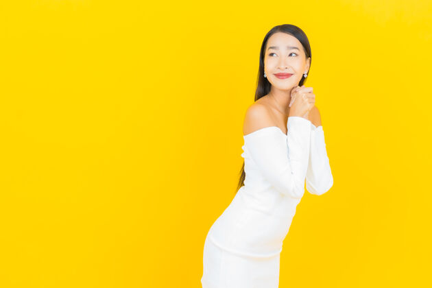 微笑美丽的亚洲年轻商业女性在黄色墙壁上穿着白色裙子微笑的画像工人成人肖像