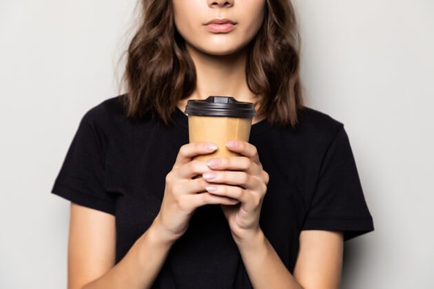 一次性年轻漂亮的女人提供白色咖啡杯隔离在灰色的墙上印度人脸微笑