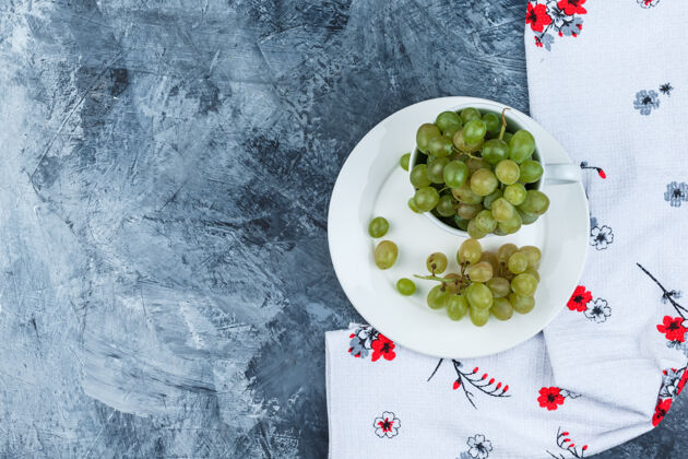 健康一些绿色的葡萄在白色的杯子和盘子上涂上厚厚的灰泥和厨房毛巾 平铺着咕噜葡萄藤饮食