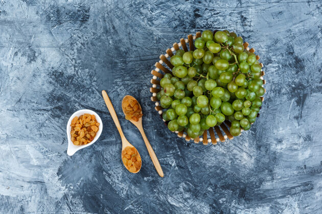 饮食绿色的葡萄在一个篮子里 葡萄干平放在一个肮脏的石膏背景上篮子藤蔓食物