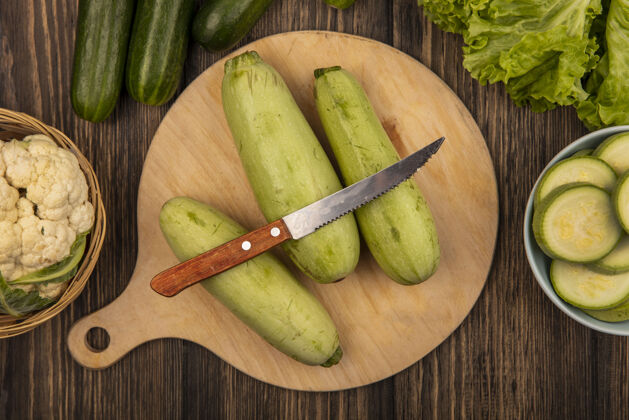 黄瓜西葫芦的俯视图被隔离在木制的菜板上 刀子和菜花放在木桶上 黄瓜和莴苣被隔离在木制的表面上健康饮食叶子