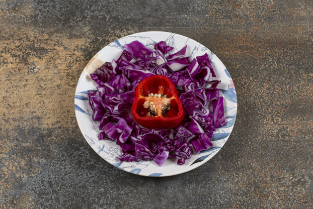 有机胡椒粉切碎在切碎的红色卷心菜盘中 放在大理石表面可口胡椒生的