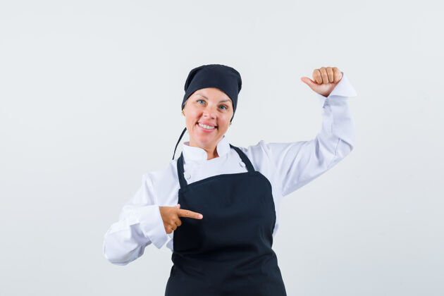 肖像女厨师穿着制服 围裙指向一边 假装拿着什么东西 看上去很高兴 前视图皮肤可爱健康
