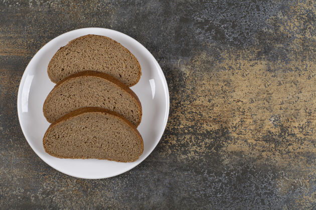 自然黑麦黑面包片放在白盘子里黑麦谷类早餐