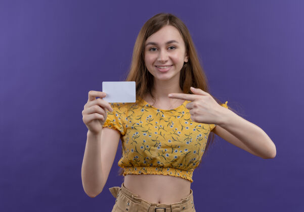 抱着微笑的年轻女孩拿着卡片 指着孤零零的紫色墙上的卡片微笑指着年轻