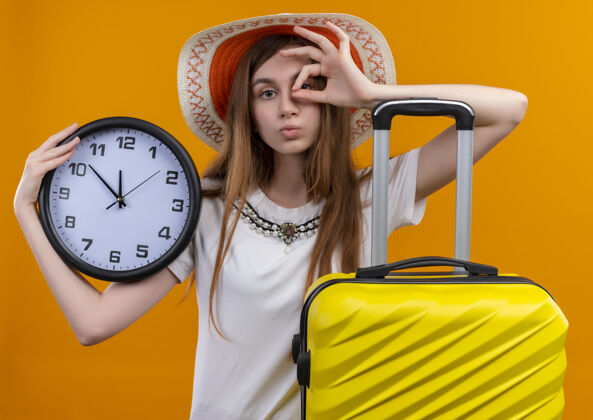 女人年轻的旅行女孩戴着帽子 手提箱在孤立的橙色墙上手提箱帽子穿