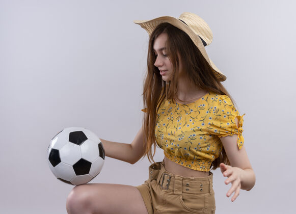 年轻戴帽子的小女孩在孤零零的白墙上玩足球女孩女人球