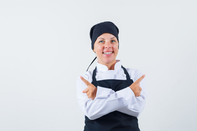 烹饪身着制服的女厨师 围裙指向别处 看上去兴高采烈 俯瞰前方女士成人时尚