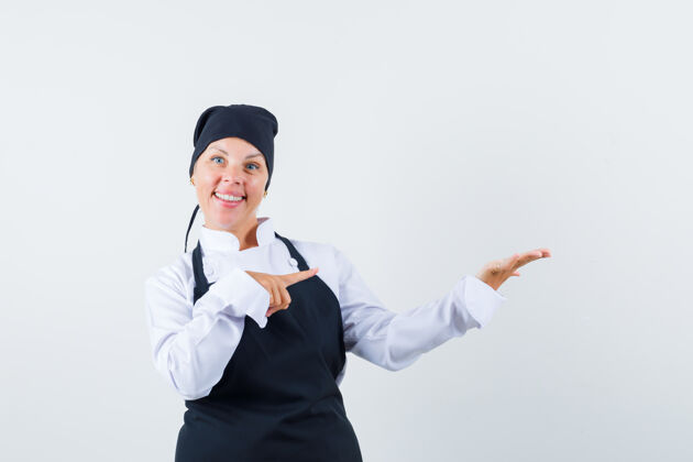 欢呼穿着制服的女厨师 围裙指着她摊开的手掌 看上去很自信 正对着前方时尚肖像手掌
