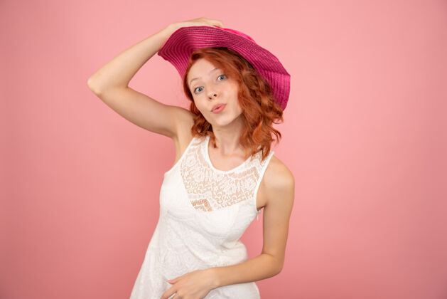时尚浅粉色墙壁上戴着粉色帽子的年轻女性的正视图航行旅行女人